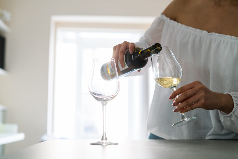 kobieta nalewająca białe wino